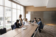 © fizkes - Young attractive European business coach hold training for staff members, gathered in modern meeting room. Multinational business team exchanging opinions and ideas take part in briefing led by female