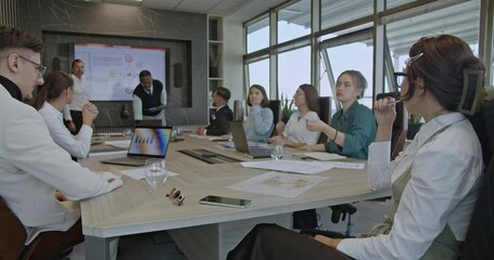 Wall Mural - Multicultural colleagues discuss charts and diagrams during a business meeting in a modern office. Teamwork and collaboration in a diverse workplace.