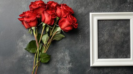 Wall Mural - A bouquet of vibrant red roses is beautifully arranged next to a simple white frame on a dark, textured surface. This setting evokes feelings of love, creativity, and artistic expression