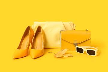 Wall Mural - Yellow high heels with stylish bags, sunglasses and autumn leaf on color background