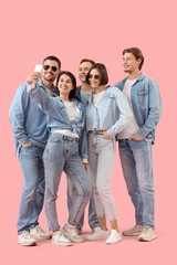 Wall Mural - Group of young people in denim clothes taking selfie on pink background