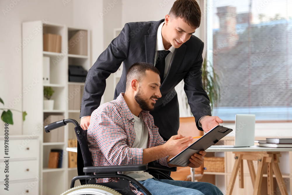 Young lawyer with man in wheelchair signing document at office