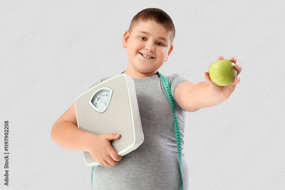 Overweight boy with scales and apple on light background. Diet concept