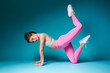 © Oksana - Fit woman in bright sports outfit holding plank pose with raised leg on vibrant background. Fitness concept
