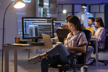 Wall Mural - female programmer working with laptop in office at night