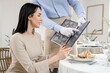 © Pixel-Shot - Young waiter showing menu to woman in restaurant