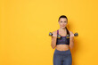 © New Africa - Smiling woman with dumbbells training on yellow background. Space for text