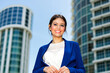 © Minerva Studio - Smiling businesswoman posing in front of modern office buildings