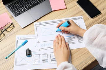 Wall Mural - website designer creating wireframe on paper with highlighter at wooden table, above view