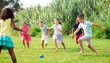 © JackF - International group of active tweenagers having fun together outdoors, playing football on green grass in summertime