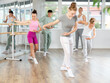 © JackF - Slim adolescent female attendee of ballet courses training ballet steps under control of ballet-master in dancehall