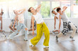 © JackF - Young girl in bright clothes, together with group of teenage friends, learn to dance hip hop in choreographic hall. Students move to modern music, do moonwalking, squats, bends, work with body