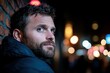 © Milos - A bearded man glances back over his shoulder with intrigue, exuding confidence and mystery against a backdrop of multicolored lights and brick walls at night.