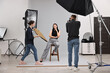 © New Africa - Photographer and assistant working with model in professional photo studio