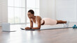 © Prostock-studio - Online Workout. Smiling Sporty Sporty Lady Standing In Plank Position On Floor Mat At Home, Looking At Laptop Watching Video Tutorial. Cheerful Lady Exercising. Domestic Fitness, Banner, Panorama
