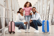 © Prostock-studio - Happy Loving Family Of Three People Of Color Embracing In Airport Terminal While Waiting Flight, Cheerful Daughter Hugging Her Parents, Family Posing With Suitcases Looking At Camera In Lounge Zone