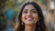 © AKSNA - Close Up Portrait of a Young Indian Woman in Professional Suit with Radiant Smile and Warm Expression on Light Blue Background