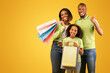© Prostock-studio - Black friday concept. Happy black parents and cute daughter holding shopper bags, man showing thumb up while posing together over yellow background. Family enjoying seasonal sales
