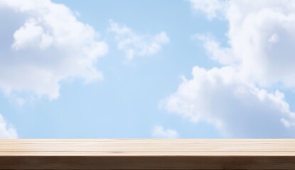 Wall Mural - empty wooden table against a bright blue sky with fluffy clouds.