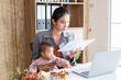 © Rakchanok - Beautiful Asian single mother in a gray suit holding newborn baby on her lap using laptop to work at home and waiting for online meeting. small business startup entrepreneur, Childcare and working mom