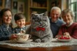 © NATURALFAMILY - Cat in red bow tie drinks milk with family nearby