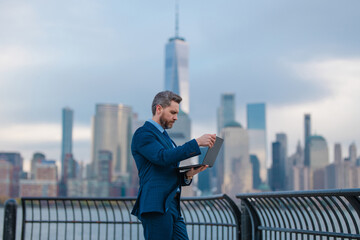 Wall Mural - Business man at the city. Business man with laptop on streets of New York City's financial district. Businessman at Manhattan. Business man works on laptop outdoor. Business in NYC.