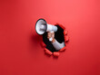 © YiuCheung - A hand holding a megaphone bursts through a red paper background, announcing an urgent message.  The scene is minimalist and impactful, symbolizing a powerful announcement or call to action.