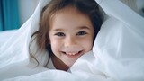 Smiling Girl Under Cozy White Blanket. International Day of Happiness. Children's Day. Family Day. 