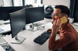 © Zamrznuti tonovi - Programmer talking on mobile phone while working on computer in office