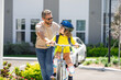 © Volodymyr - Happy fathers day. Father and son learning to ride a bicycle having fun together at Fathers day. Father teaching his son cycling on bike in american neighborhood. Father and son concept. Father