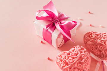 Wall Mural - Pink hearts and gift box with ribbon on a light pink background