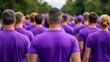 © fotogurme - A crowd walking together in a World Cancer Day awareness walkathon all wearing purple shirts and holding banners with motivational messages