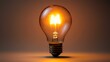 © Desi - Glowing incandescent bulb studio shot, bright filament, dark background, idea concept