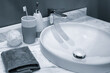 © Aleksandr Matveev - bathroom sink with a white basin and a silver faucet. A white towel is placed on the counter next to the sink. A toothbrush and a bottle of soap are also present on the counter