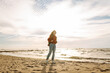 © maxbelchenko - Portrait of a beautiful woman with backpack on the beach in cold weather. Autumn near the sea. Calmness and tranquility. Travel, tourism concept.