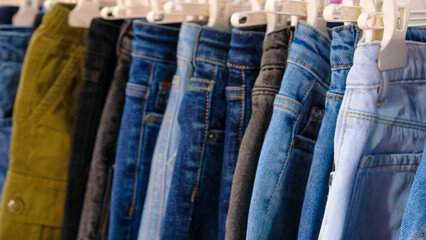 Poster - A row of jeans hanging on a rack. The jeans are of different colors and styles. Concept of variety and choice, as the person hanging the jeans can pick and choose from the different options available