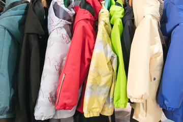 Poster - A row of colorful jackets hanging on a rack. The jackets are of different colors and styles, including red, yellow, green, and blue. The jackets are neatly arranged