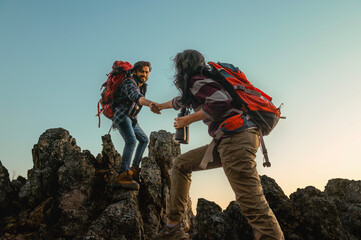 man and a woman are helping each other climb a mountain