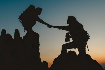 man and woman are climbing a mountain together