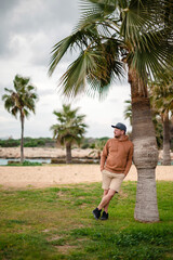 Wall Mural - Man Relaxing by Palm Tree at Beach