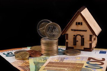 Symbolic wooden house, 50, 100, 200 euro bills and Euro coins of various denominations