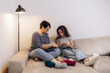 © Roman - Mum teaches her daughter to knit while sitting on the sofa