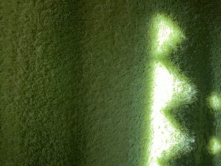 Poster - subtle sunlight creating geometric patterns on textured green towel fabric, perfect for abstract designs, background concepts, or natural themes