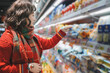 © zhouyilu - Young Woman Shopping for Groceries in a Colorful Supermarket Aisle