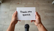 © Larisa - Thank you speech card held in hands above a microphone