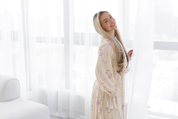 charming caucasian female with a smile in a black dress by the window