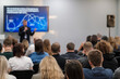 © Anton Gvozdikov - Professional speaker engaging audience during business conference presentation with visual aids displayed on screen.