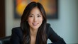 © Wilasinee - Confident and Successful Asian Businesswoman Leaning on Her Desk with a Warm Smile in Her Corporate Office Environment