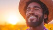 © Vertigo Images - A happy Black man smiles broadly at sunset, wearing a wide-brimmed hat.