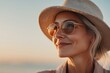© c80 - Woman enjoying a sunset at the beach with a relaxed smile while wearing a hat and sunglasses